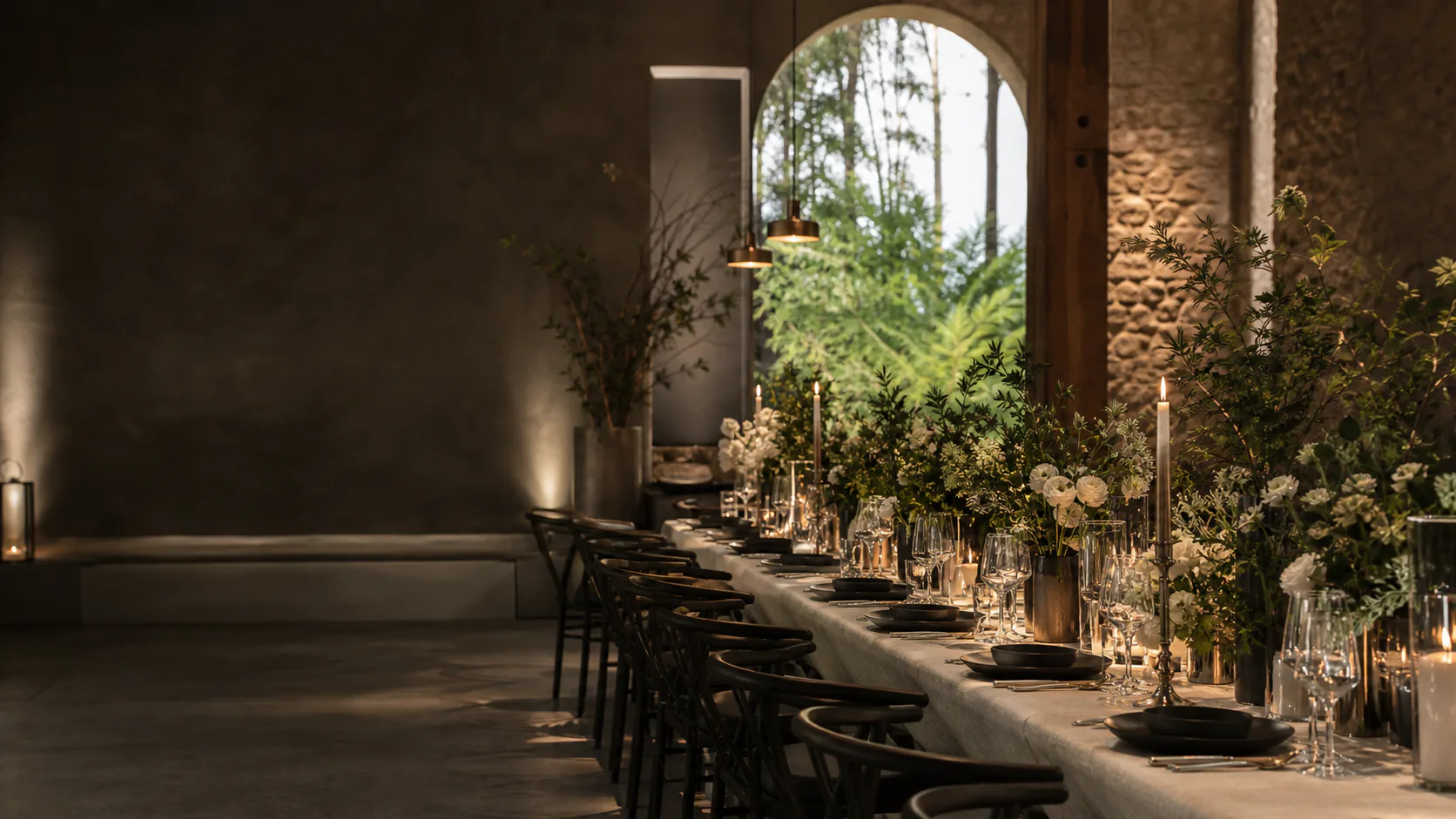 Réception de mariage contemporaine dans un lieu en pierre, table ivoire, végétation et bougies.